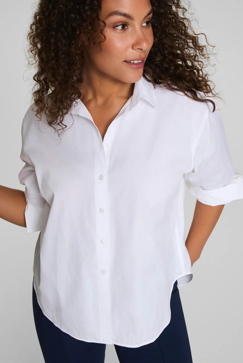 Woman wearing a white button-up shirt against a plain background