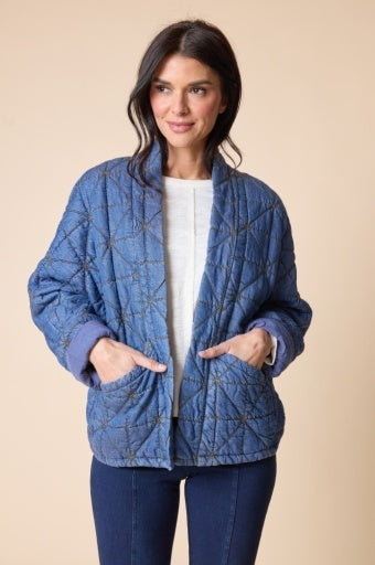 Woman wearing a blue quilted jacket on a beige background