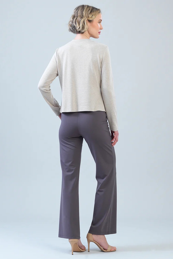 A woman is shown from the back wearing a light beige long-sleeve cropped sweater and dark gray wide-leg trousers, paired with nude high-heeled sandals, against a light gray studio background.