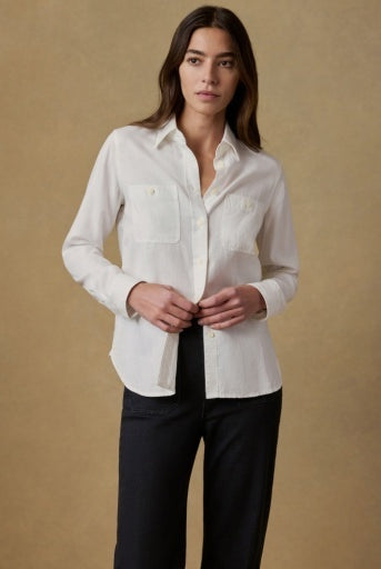 Woman wearing a white shirt and black pants against a beige background