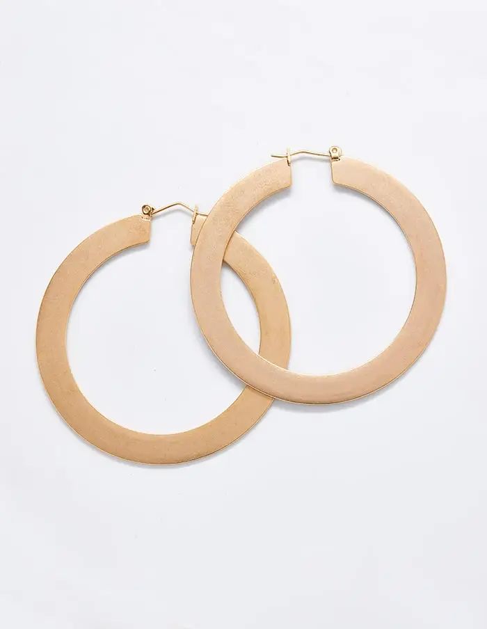 Pair of large matte gold-tone hoop earrings on a light background