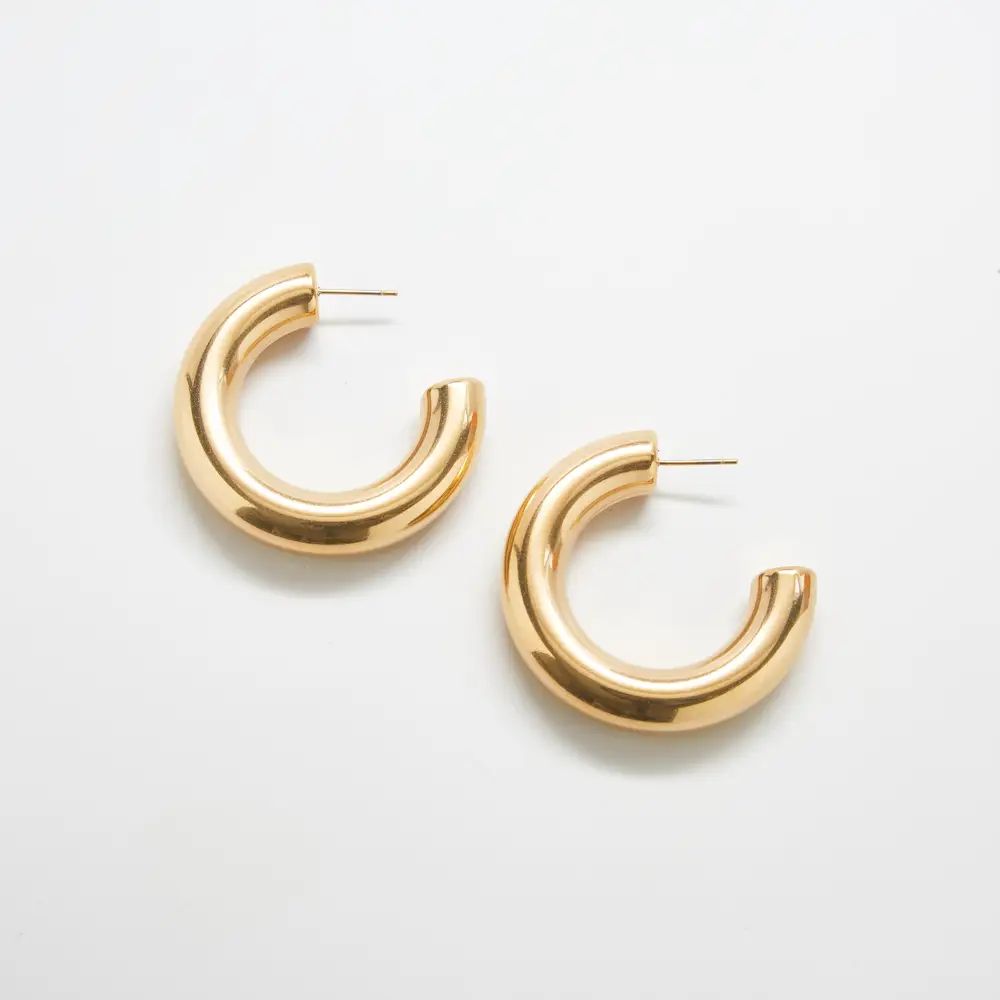 Pair of medium chunky gold-tone hoop earrings on a light background
