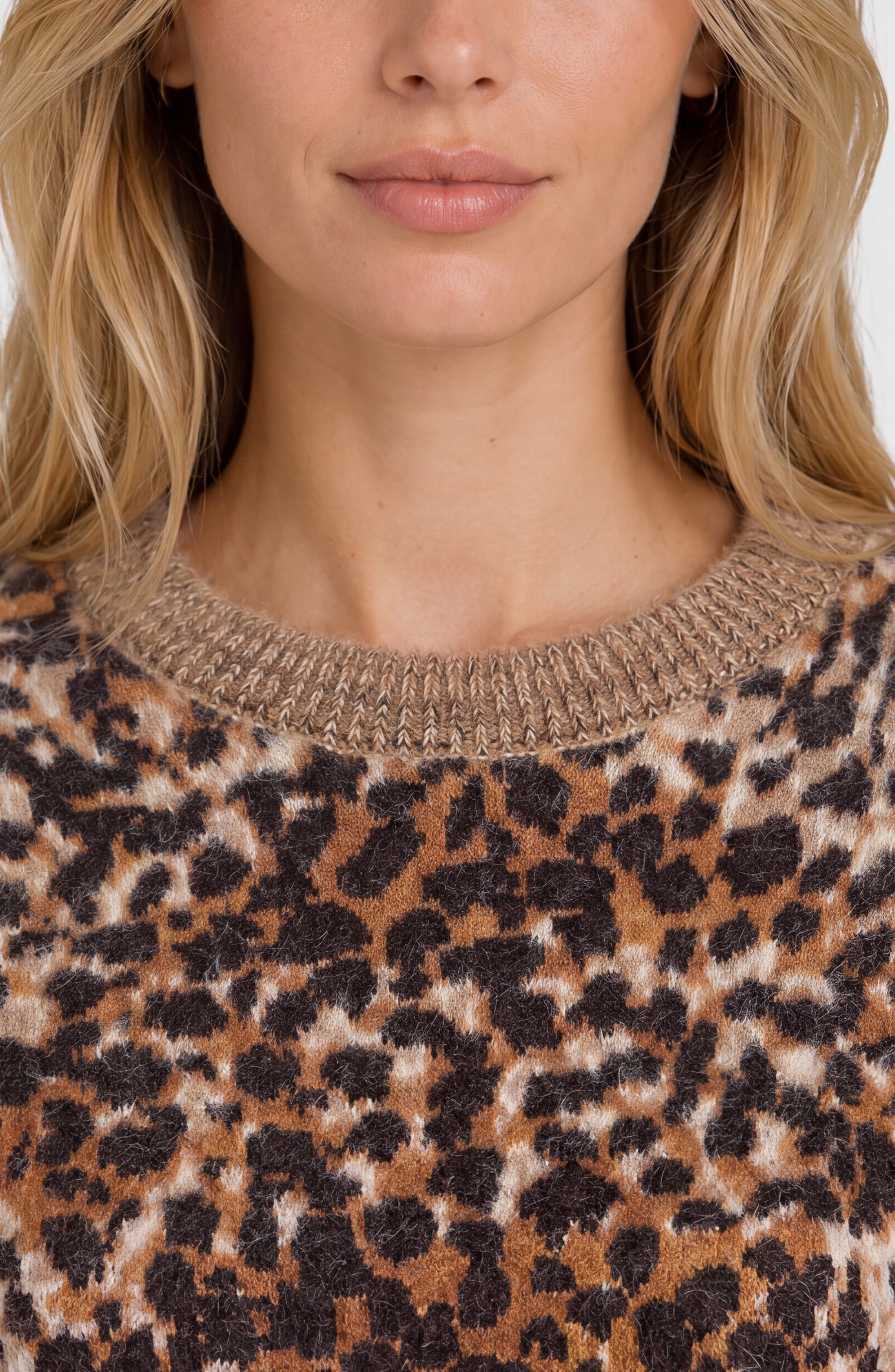 Close-up of a woman wearing a fuzzy knit crewneck sweater with a brown, black, and beige leopard print pattern.