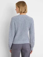 A woman shown from the back wearing a light heather gray knit sweater and dark gray pants against a plain white background.