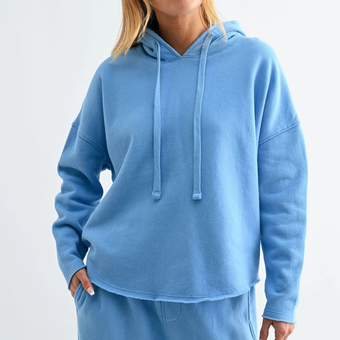 Woman wearing a blue hoodie and pants on a white background