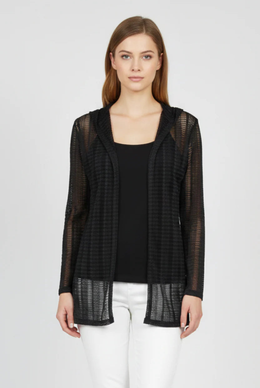 Woman wearing a black sheer jacket over a black top and white pants on a white background
