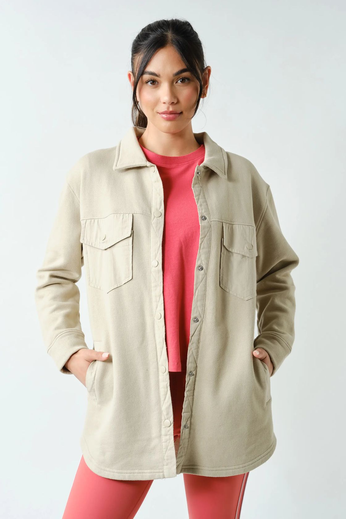 woman wearing off white shacket with hot pink top and pants with white background