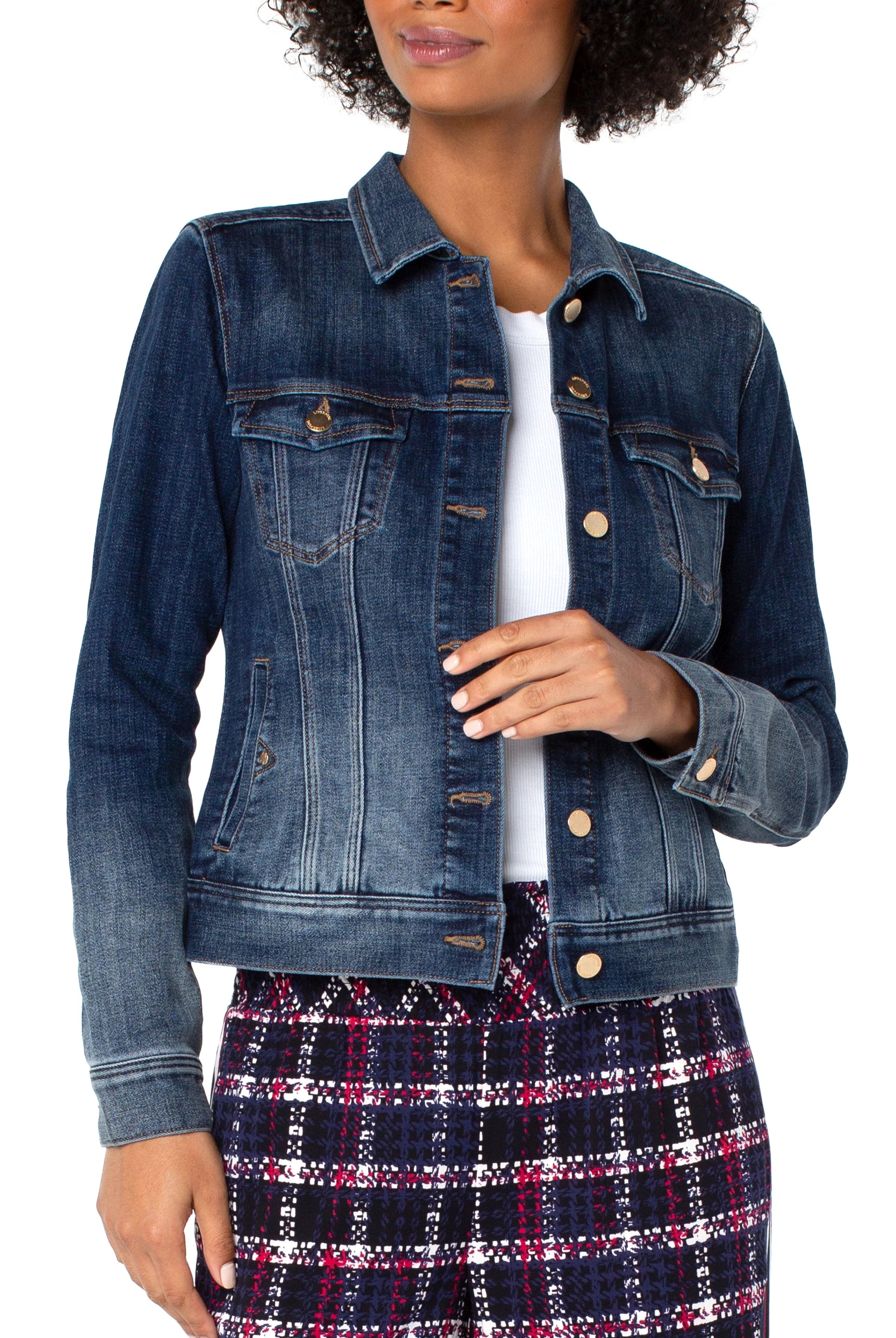 Woman wearing a blue denim jacket over a white shirt and plaid skirt on a white background