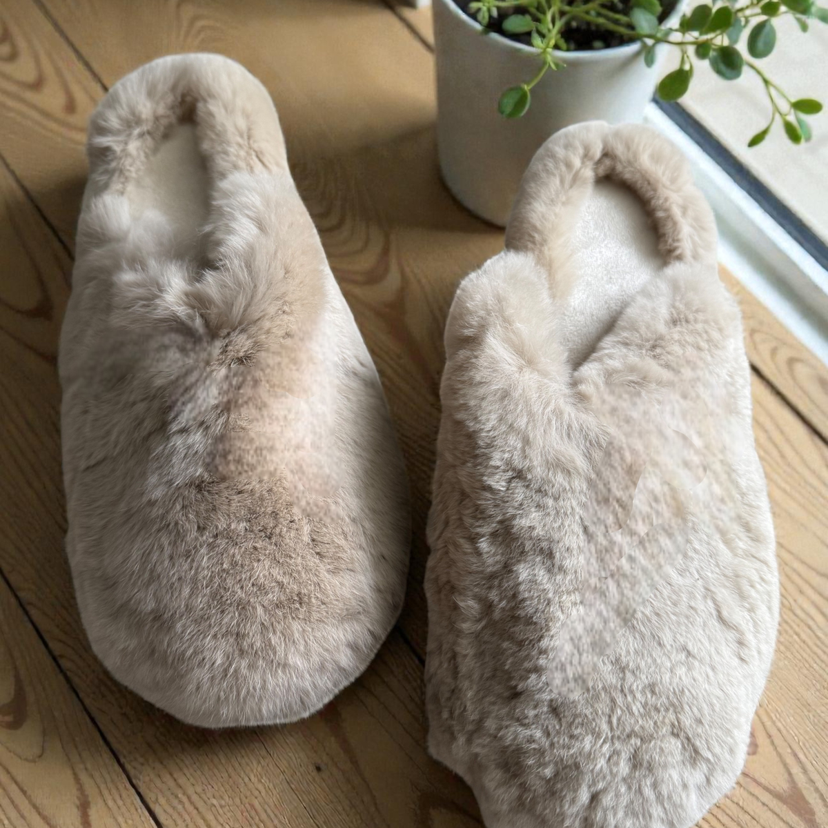 Beige rabbit fur slippers on a cozy rug
