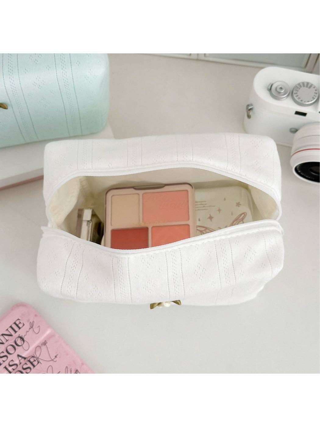 Open textured cosmetic pouch filled with makeup