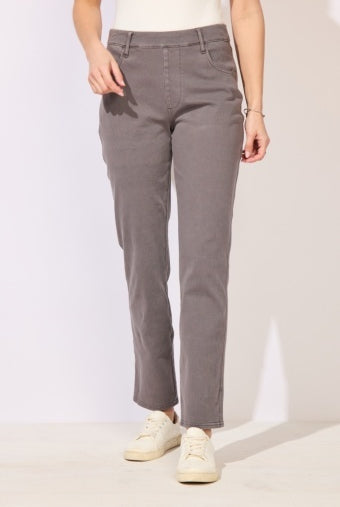 A person wearing straight-leg gray pants with a white top and white sneakers, standing against a plain light background.