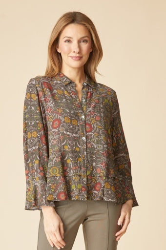 Woman wearing the Habitat Rayon Crepe Garden Flounce Shirt, olive floral button-front with flounce hem and cuffs, with olive trousers