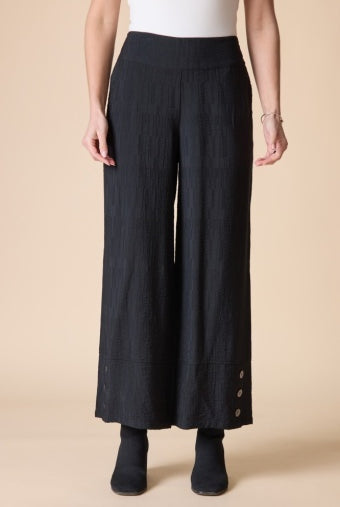 Woman wearing the Habitat Rayon Jacquard Button Hem Pant, black textured pull-on wide leg pant with a white top