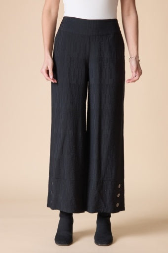 Woman wearing the Habitat Rayon Jacquard Button Hem Pant, black textured pull-on wide leg pant with a white top