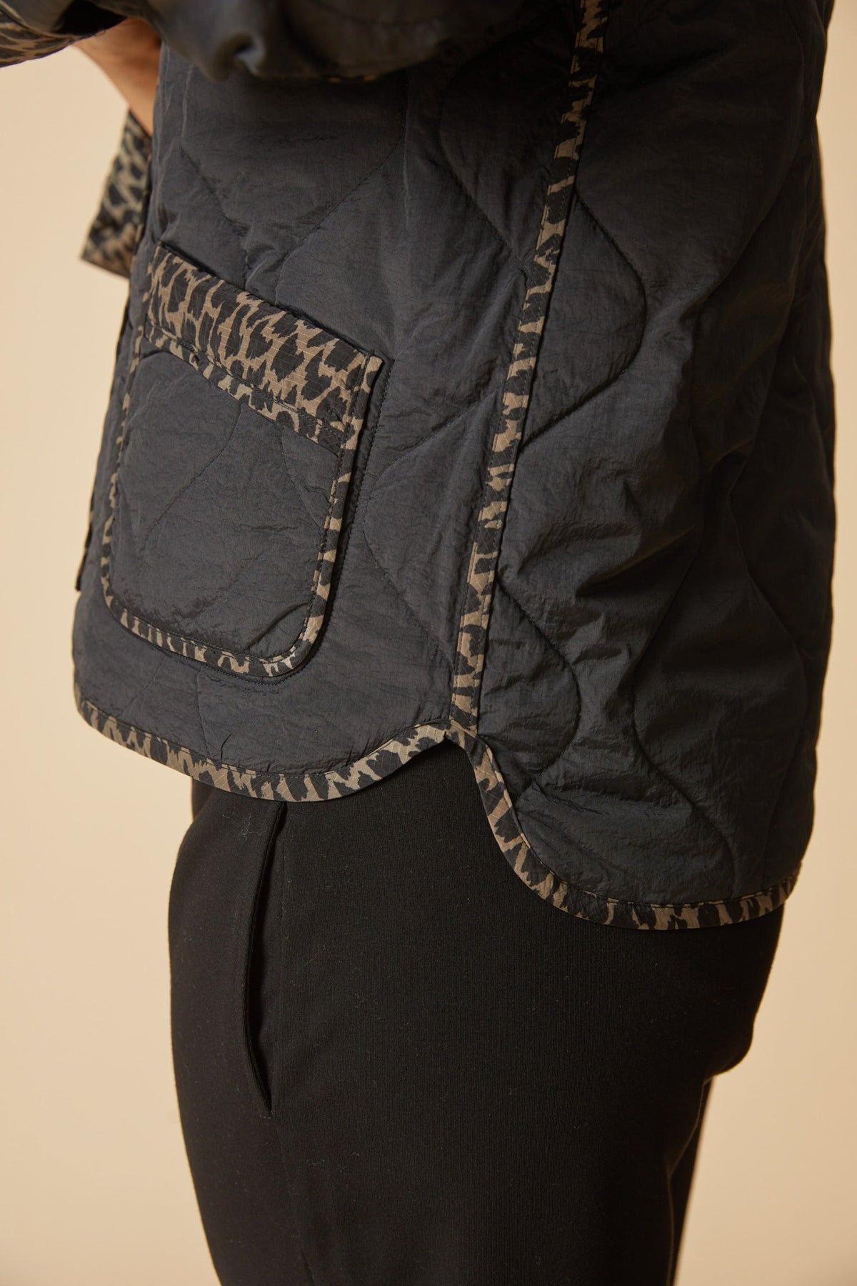 Close-up of the Habitat Reversible Print Quilt Puffer Coat pocket and hem with animal print trim on black quilting