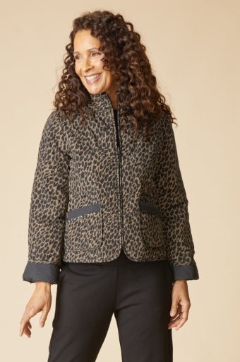 Woman wearing the Habitat reversible quilted puffer coat, animal print side out with stand collar, zip front and solid black cuffs