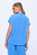 A woman wearing a bright blue short-sleeve scrub top and matching pants, shown from the back against a plain white background.