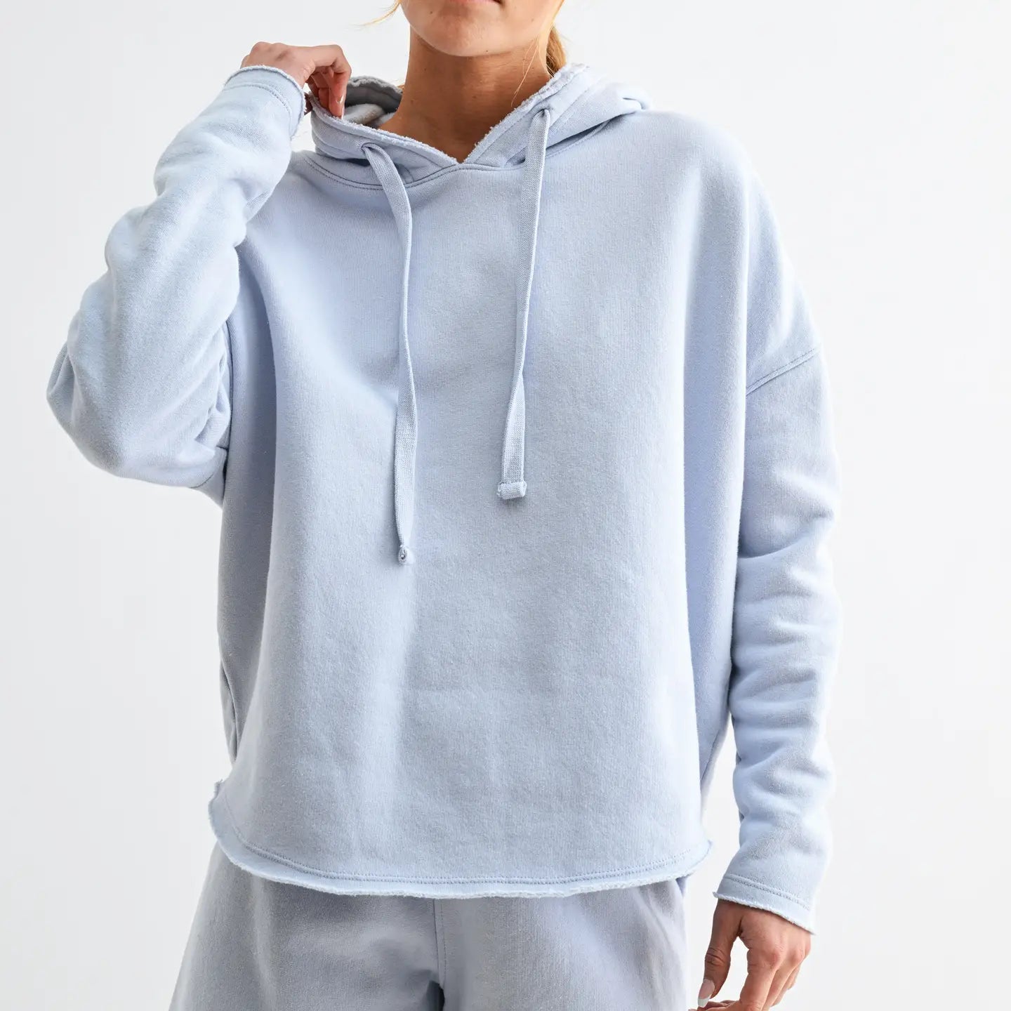 woman wearing a light blue hoodie and shorts set with white background