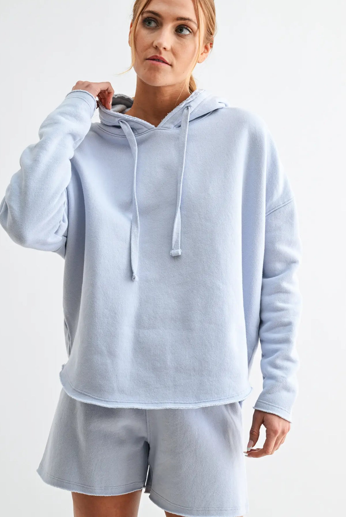 woman wearing a light blue hoodie and shorts set with white background