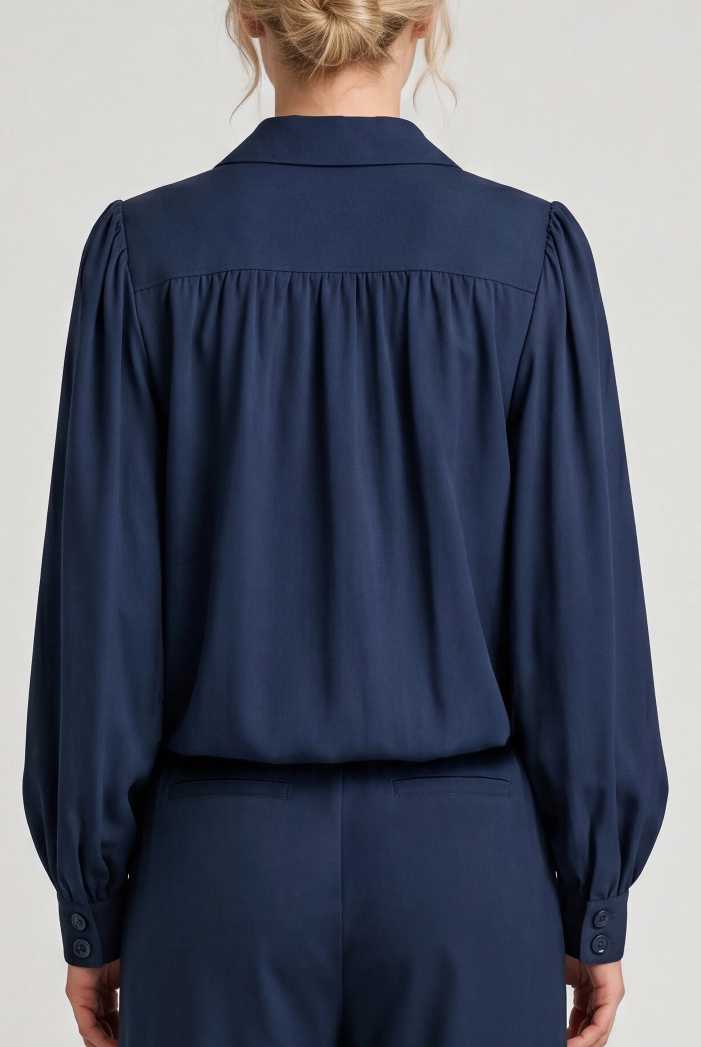 Navy blue blouse worn by a person on a light gray background