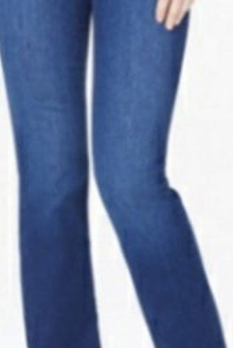 A woman modeling NYDJ Barbara Bootcut petite jeans in Quinn medium blue wash, paired with a white top and beige heeled sandals, against a plain light studio background.