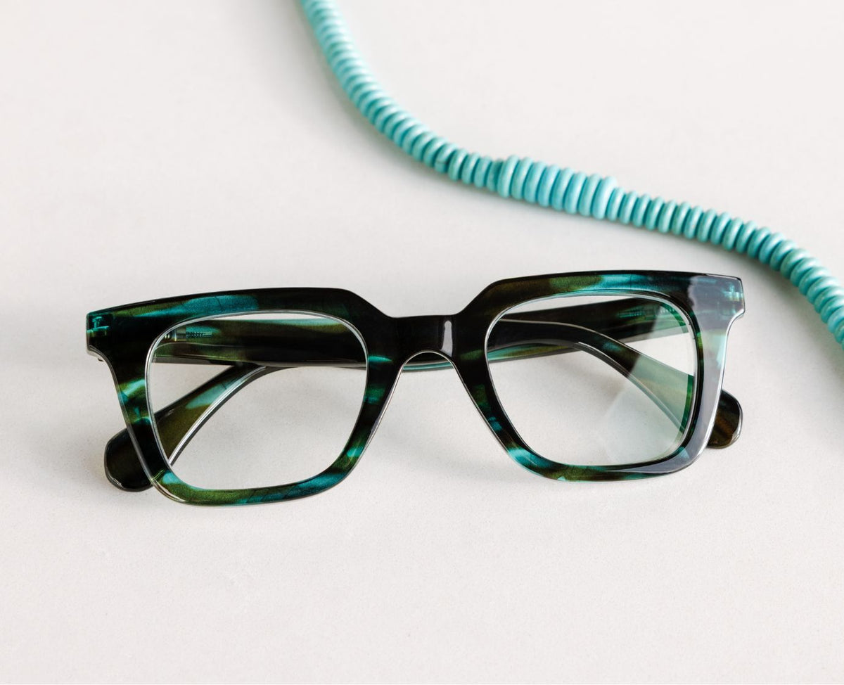 Peepers Page reading glasses in Teal Horn, styled flat lay