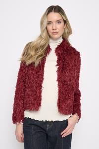 Woman wearing the Picadilly Faux Feather Short Jacket in Cabernet, a cropped plush jacket with a stand collar, over a cream mock-neck top and dark jeans