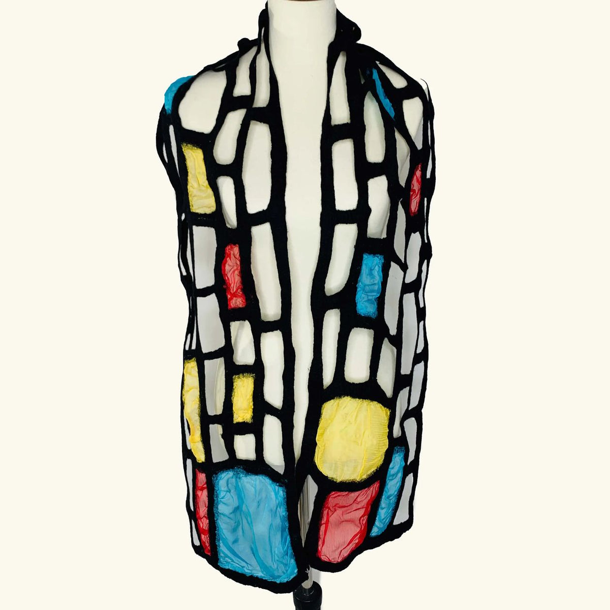 Pomegranate Moon Mondrian Inspired hand-felted silk and wool scarf with blue, yellow and coral color blocks outlined in black, displayed on a dress form