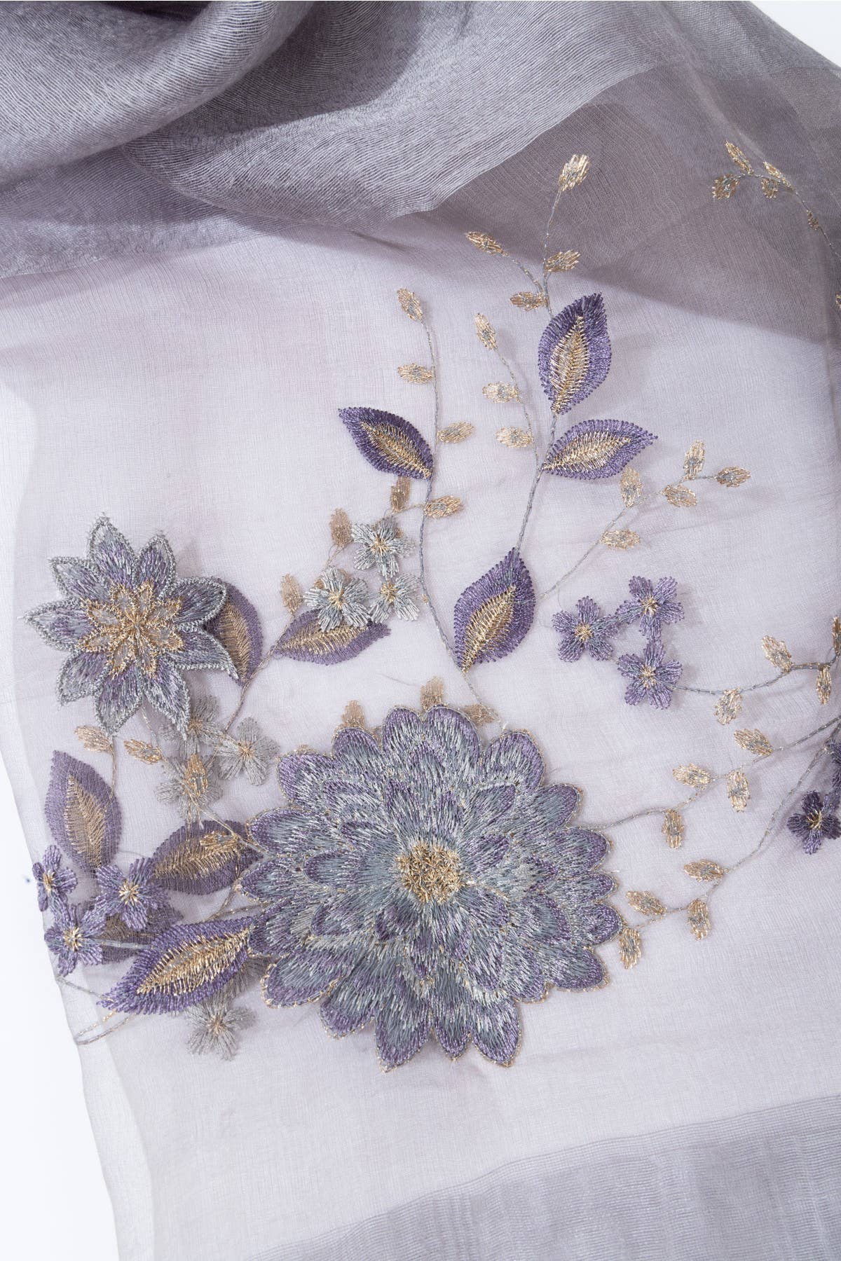 Close-up of floral embroidery on the grey sheer scarf
