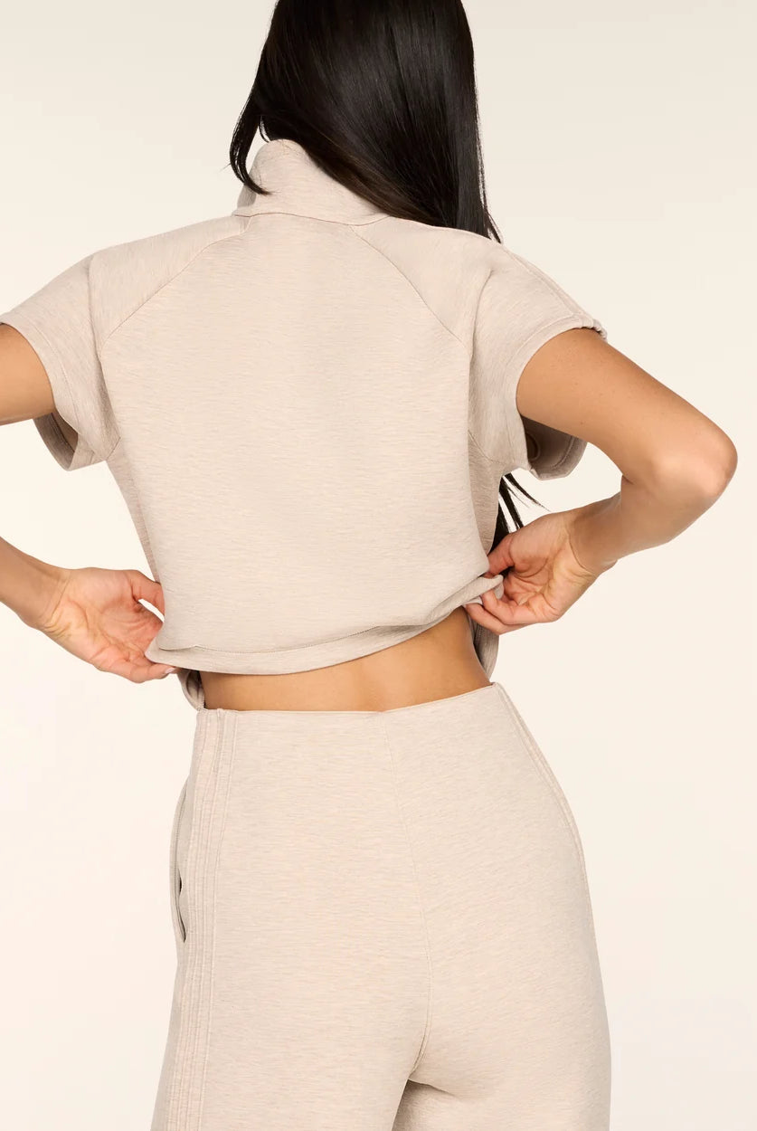 Back view of the Spanx AirEssentials Pintuck Half Zip Jumpsuit in Bone Heather with the top lifted to show the hidden back opening for easy bathroom breaks
