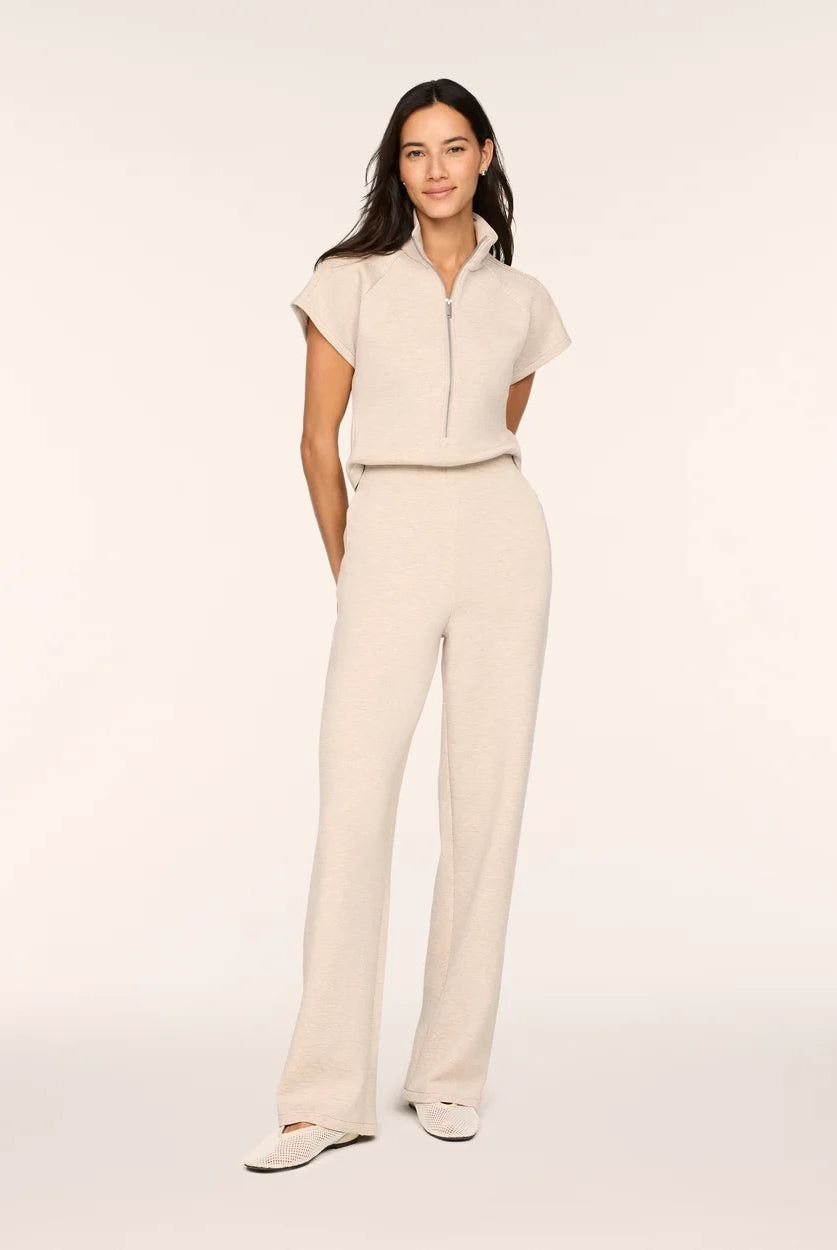 Full-length front view of a woman wearing the Spanx AirEssentials Pintuck Half Zip Jumpsuit in Bone Heather with short sleeves, half-zip collar, pintucked relaxed wide legs and ballet flats