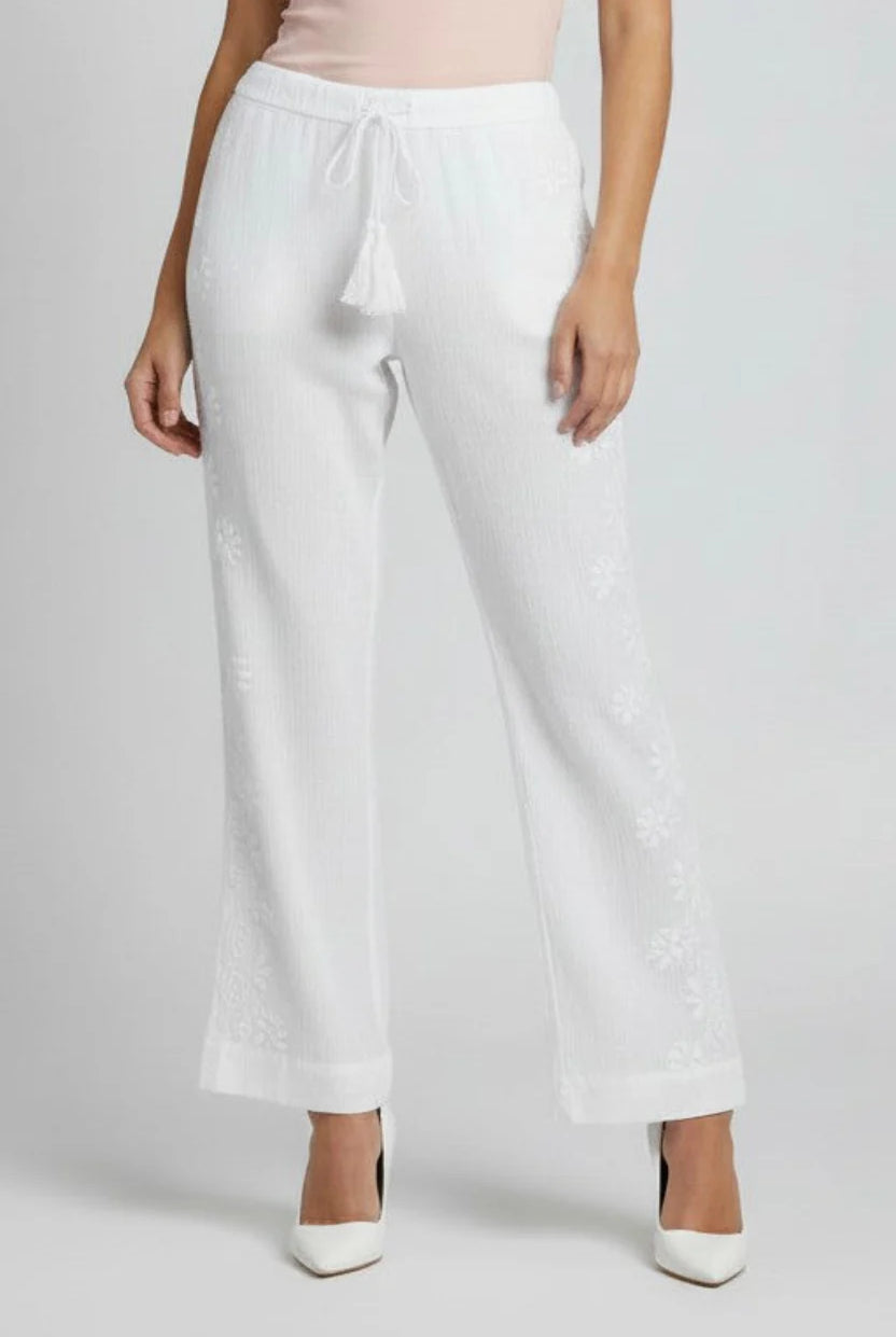 White wide-leg pants with embroidered floral details down the sides and a drawstring waist, shown on a model against a light gray background.