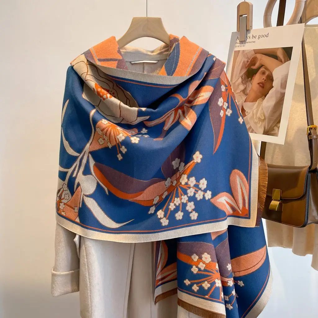 Winding River Cozy Cashmere Feel Travel Reversible Shawl in cobalt blue and burnt orange botanical print with cream border, draped on a hanger