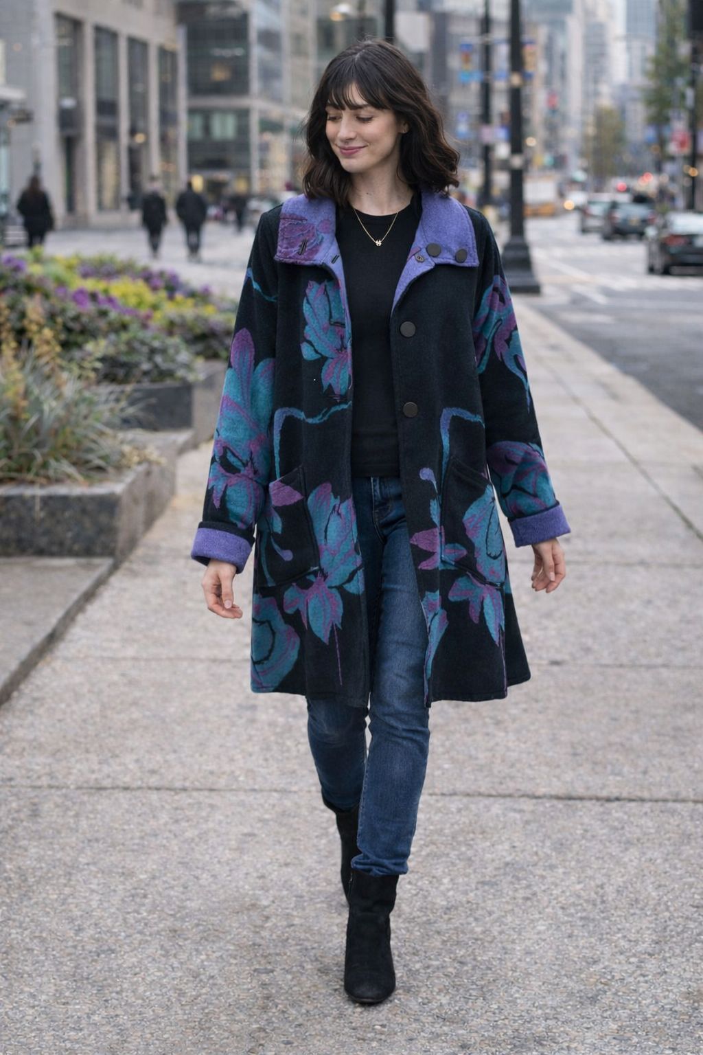 Winding River Reversible Coat from the Lotus Collection in black with purple and teal lotus print and purple collar, worn walking on a city sidewalk