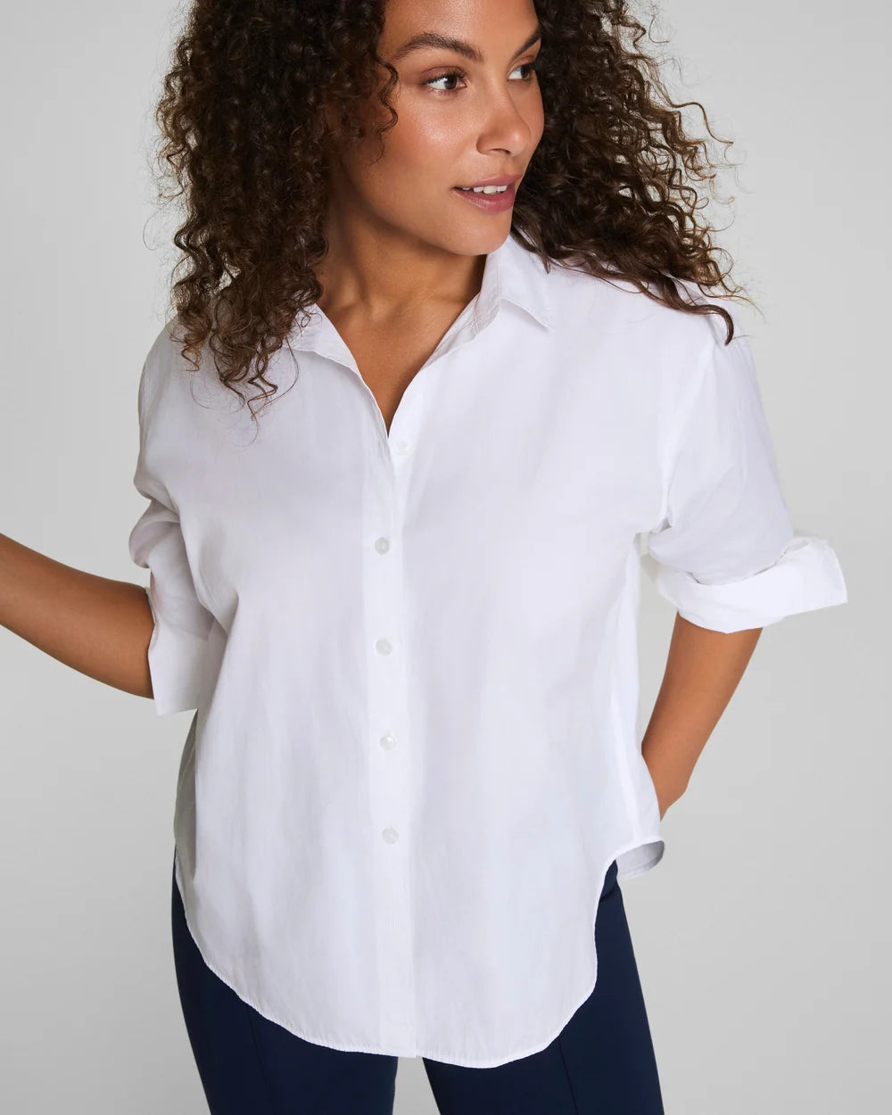 Woman wearing a white button-up shirt against a plain background