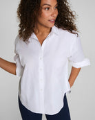 Woman wearing a white button-up shirt against a plain background