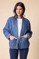 Woman wearing a blue quilted jacket on a beige background