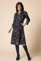 Woman wearing a floral dress with long sleeves on a beige background
