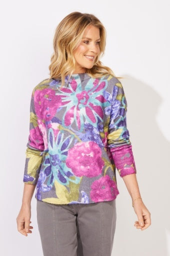 Woman wearing a colorful floral-patterned top against a white background