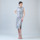 Woman wearing a silver sleeveless dress on a plain background