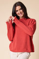 Woman wearing a red sweater against a beige background