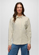 Stretch Zion LS Button Up in Beach Pebble, woman modeling a light beige long-sleeve button-up shirt with a chest pocket, paired with blue pants, against a solid light gray background