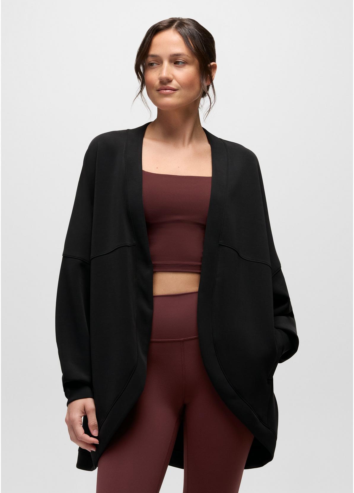 A woman modeling a black open-front cardigan over a matching burgundy activewear set against a light gray studio background.