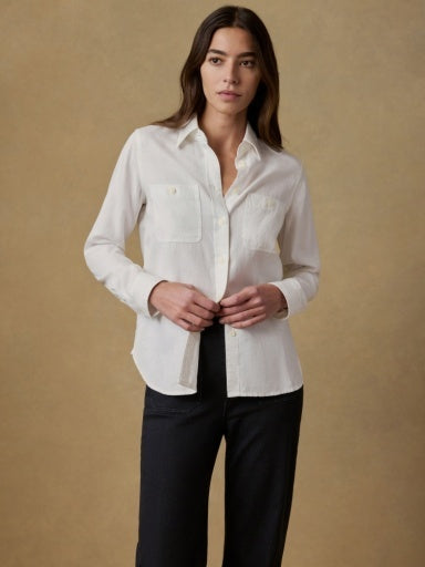 Woman wearing a white shirt and black pants against a beige background