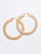 Pair of large matte gold-tone hoop earrings on a light background