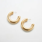 Pair of medium chunky gold-tone hoop earrings on a light background