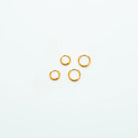 Two pairs of mini gold-tone huggie hoop earrings on a light background