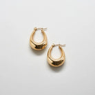 Pair of gold-tone oval hoop earrings on a light background
