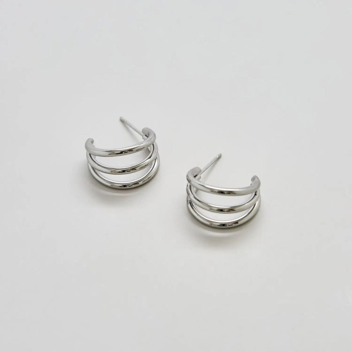 Silver triple arc hoop earrings on a white background