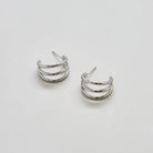 Silver triple arc hoop earrings on a white background